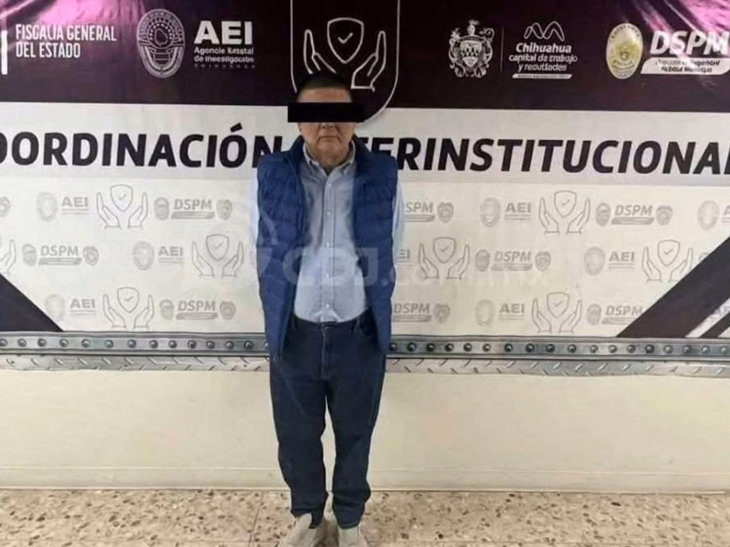 hombre-con-chaleco-azul-y-los-ojos-cubiertos-frente-a-una-manta-de-la-fiscalia-general-del-estado-de-chihuahua